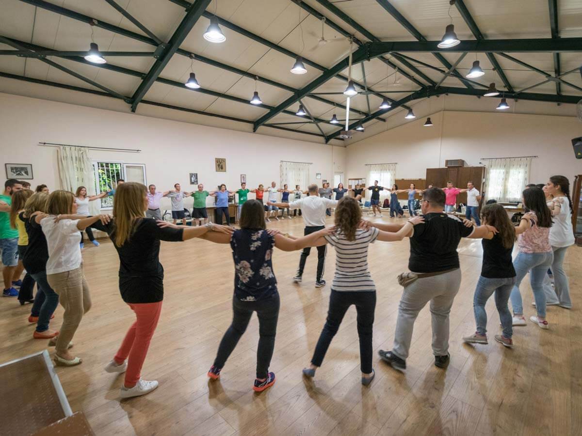 People shoulder to shoulder dancing Greek fold dances